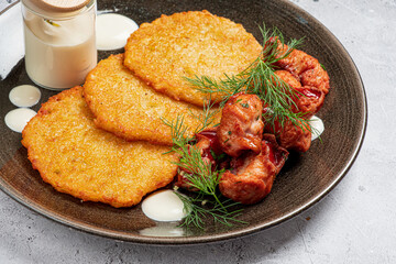 Delicious potato pancakes accompanied by perfectly cooked meatballs and a drizzle of creamy sauce