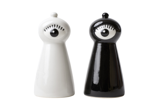A playful pair of black and white ceramic salt and pepper shakers, each featuring a stylized eye design, on a transparent background. background removed