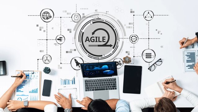 A diverse team engages in project management using laptops and digital tools. The workspace displays charts and data, showcasing innovative strategies and collaboration in action. Raster