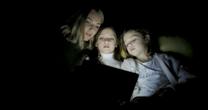Woman and two girls using digital tablet at home to read ebook and remote learning