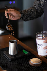 Coffee beans being poured into a metal container on a scale.