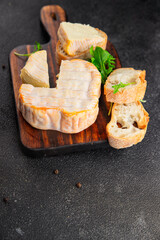 Washed rind cheese soft cheese with orange rind munster french cheese tasty snack fresh delicious gourmet food background on the table rustic top view copy space