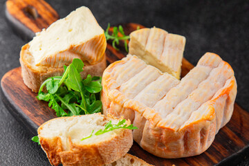 Washed rind cheese soft cheese with orange rind munster french cheese tasty snack fresh delicious gourmet food background on the table rustic top view copy space
