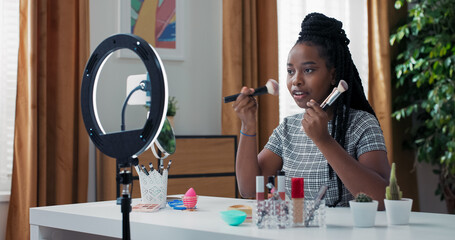 Beginner films beauty video using ring light and phone. Popular makeup artist shows foundation and...