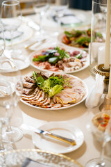 Beautifully arranged sliced meats and fresh greens on elegant plates at the celebration