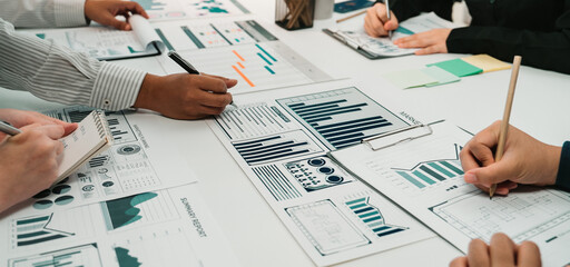Close-up view of a collaborative team engaging in data analysis with charts and graphs, showcasing teamwork and strategic planning in an office environment. SACTR
