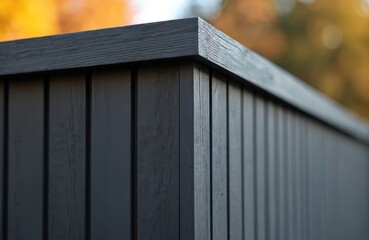 Dark grey composite wood paneling corner. Black wood grain texture. Exterior siding for modern house construction. Close-up of dark grey composite wood paneling. Wooden fence wall with dark grey
