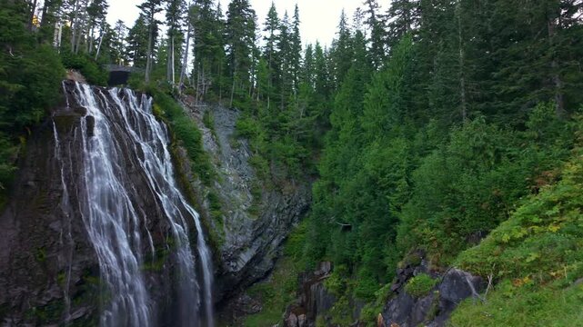 A scenic view of the beautiful Narada Falls cascading through a vibrant green forest at Mount Rainier National Park