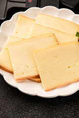 Raclette cheese portion slicing natural product tasty snack fresh delicious gourmet food background on the table rustic top view copy space