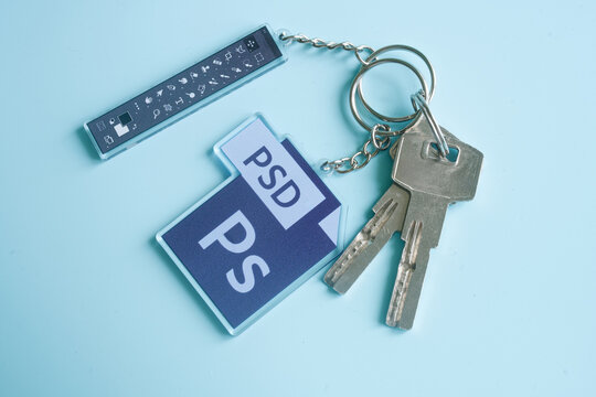 House keys with PSD file and Photoshop toolbar keychains on light blue, symbol of efficient photo editing workflow. Photo. Barcelona, Spain, October 10, 2025