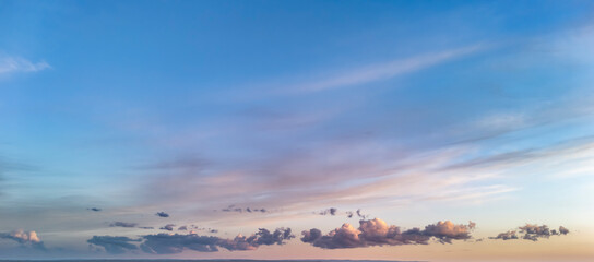 A serene sky with soft clouds and pastel colors during sunset creates a tranquil atmosphere. Perfect for landscape and nature themes in various content.