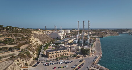 Malta: Aerial view panorama of Delimara Power Station on Marsaxlokk Bay, Malta, generating electricity under a clear blue sky. Drone flight