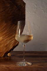 A classic still life of a glass of white wine on a rustic wooden table, with a soft, warm light.