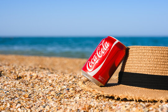 Anapa, Russia - July 11, 2025: A can of Coca-Cola on the beach. A cold drink and a straw hat on the beach.