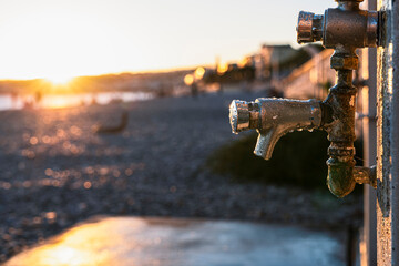 Sanitary installation with showers on the beach in Nice, photographed in the evening, with the beach and sunset in the background