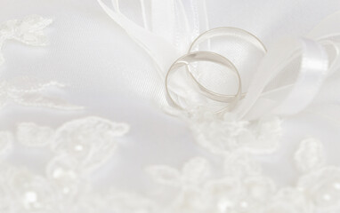 Wedding rings on a white satin pillow with embroidery decorations