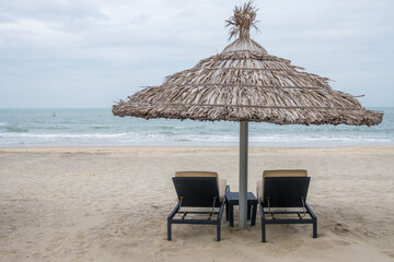 Pair of deck chairs under a palm umbrella in beautiful Cua Dai Beach in Hoi An, Central Vietnam