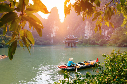 Scenic landscape of Ninh Binh with boat on river and ancient pagoda at sunset in Tam Coc National Park