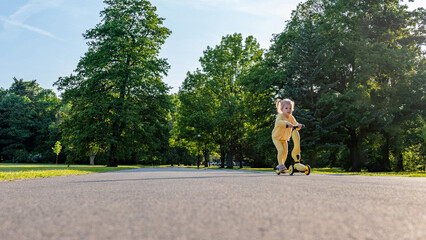 Girl on scooter. Riding child outdoor fun. Sunshine road freedom lifestyle.