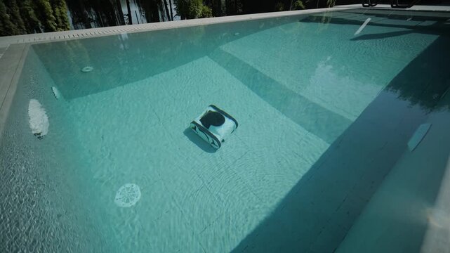 Robotic pool cleaner moving along the edge of a clear blue swimming pool