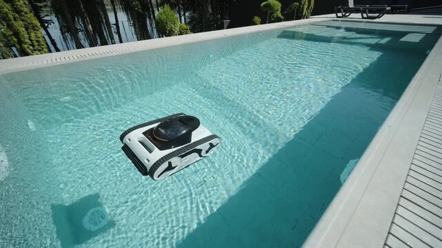 Robotic pool cleaner moving along the edge of a clear blue swimming pool