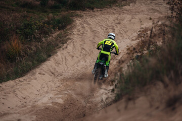 Motorcyclists on a cross-country motorcycle go fast at the desert with sands splashes