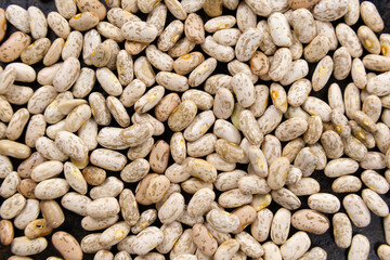 Pinto beans close up scattered over a black pan surface