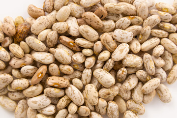 Pinto beans close up scattered over a white surface