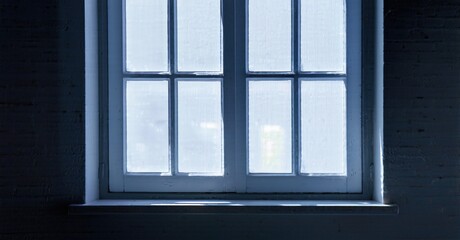 Fototapeta premium Dark room features window. Light shines through panes, creating contrast. Brick wall surrounds frame, simple composition.