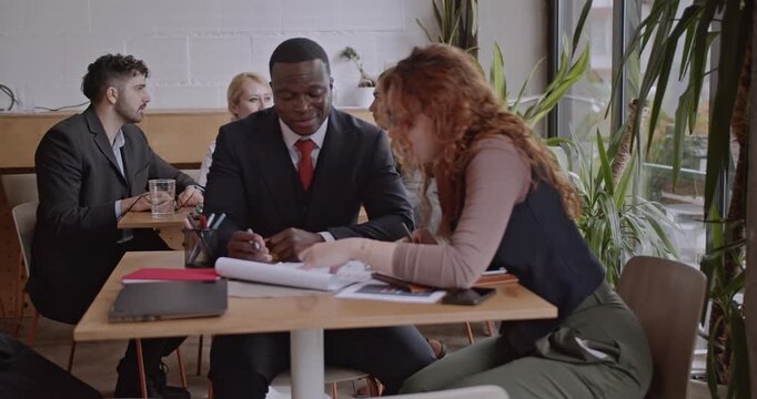 Diverse colleagues brainstorm and analyze data in a co working space. A diverse business team collaborates on a project in a coffee bar. - Powered by Adobe