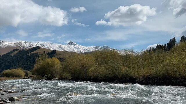 time-lapse of landscape with snow mountain and flowing river under blue sky, xinjiang, china