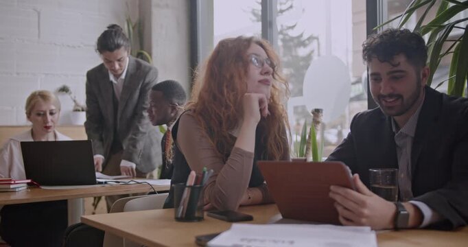 Diverse colleagues brainstorm and analyze data on a tablet in a co working space coffee bar. This diverse team collaborates on a project. - Powered by Adobe