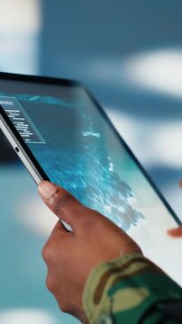 Vertical video Soldier using warning system software on tablet in control room to monitor incoming enemy aerial attacks. Army agent maintains air space superiority with radar during armed conflict