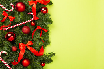 Christmas tree branches with festive decoration on color background, top view