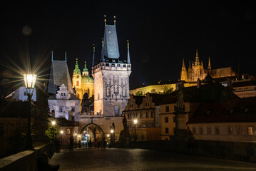 Night view of Prague with illuminated Charles Bridge, Prague Castle, and reflections on the Vltava River. Magical and historic European city after dark.