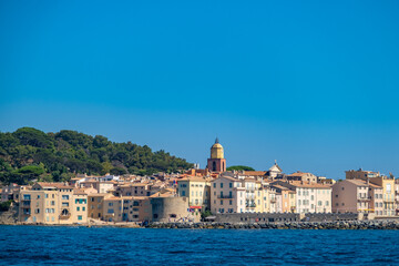 Picturesque view of Saint-Tropez harbor with luxury yachts, colorful buildings, and clear blue sky. Iconic French Riviera destination full of charm and elegance.
