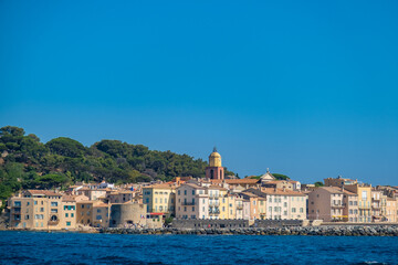 Picturesque view of Saint-Tropez harbor with luxury yachts, colorful buildings, and clear blue sky. Iconic French Riviera destination full of charm and elegance.