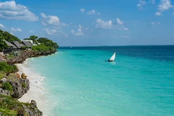 Fototapeten Sansibar Traditional wooden dhows anchored near the shore in Nungwi, Zanzibar, with turquoise waters and clear skies. Idyllic tropical seascape and cultural heritage.  © Marcio