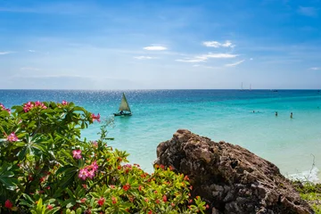 Fototapete Segeln Breathtaking view of Nungwi Beach in Zanzibar, Tanzania, featuring a traditional dhow sailing on crystal-clear turquoise waters under a vibrant tropical sky. This image captures the essence of East Af  © Marcio