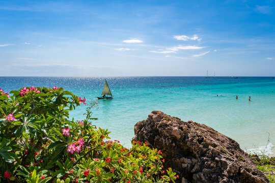 Breathtaking view of Nungwi Beach in Zanzibar, Tanzania, featuring a traditional dhow sailing on crystal-clear turquoise waters under a vibrant tropical sky. This image captures the essence of East Af