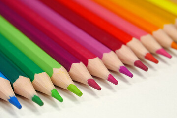 New wooden colored pencils of rainbow colors, perfectly sharpened, lie on table