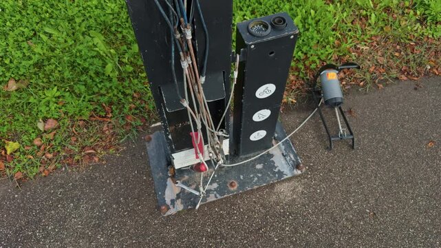 The utility pole base has been damaged, revealing exposed wiring, which poses a significant safety concern for all