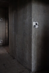 Concrete wall in unfinished building featuring calibration targets attached to surface, construction site environment visible with rough floor and exposed structure, no people present