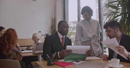 Diverse team of business professionals collaborating on project analysis and brainstorming in a modern co-working space coffee bar. - Powered by Adobe