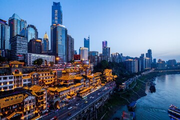 Obraz premium Nightscape of Hongya Cave Chongqing with Illuminated Buildings along the Riverfront at Dusk