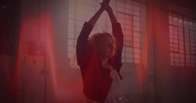 Posing dancer wearing pale tunic and dark jacket in warehouse, with grid windows and light flares - Powered by Adobe