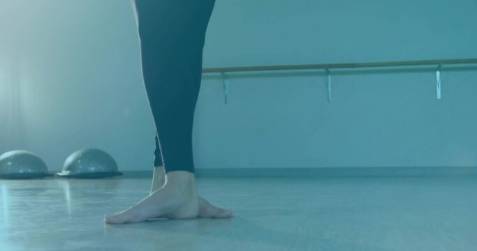 Fototapeta Balancing barefoot wearing black leggings on wooden floor in dance studio with barre, BOSU trainers
