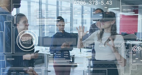 Using VR headset, woman scanning floating data panels as coworkers observe in office, copy space