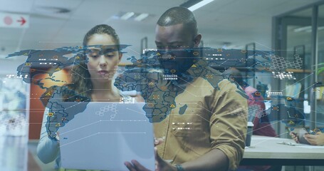 Reviewing data on laptop with world map overlay, colleagues wearing business attire in office