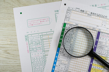 確定申告書と青色申告決算書と虫眼鏡で税務調査のイメージ